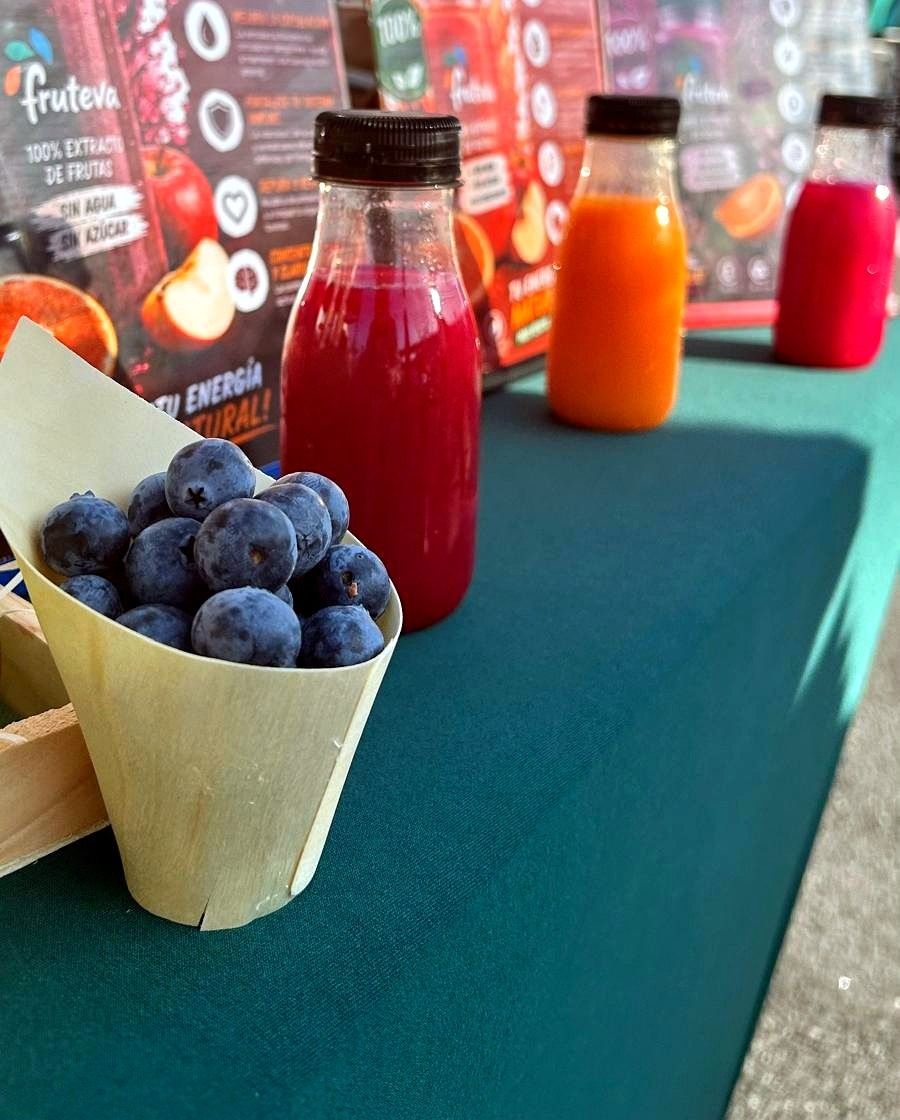 Puesto de Fruteva en un mercado con arándanos frescos y zumos naturales